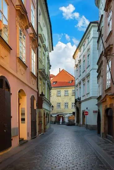 Historická dlážděná ulička v centru Prahy s barevnými fasádami chráněnými antigraffiti nátěrem